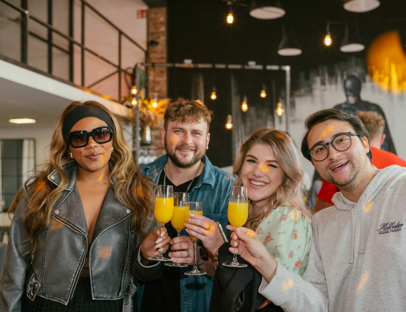 Vier Freunde stoßen mit Mimosas im Quizloft Siegburg an