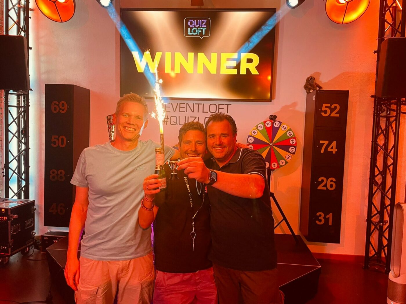 3 Männer halten Gewinn lächelnd in die Kamera