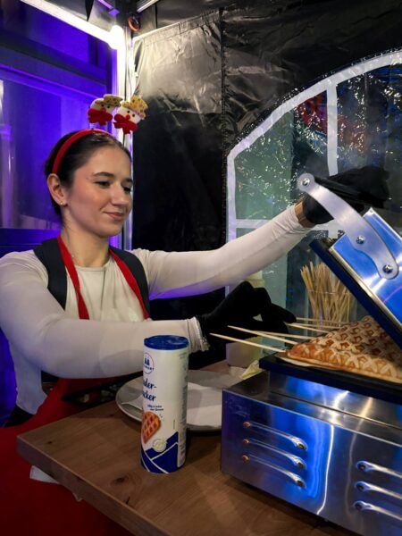 Quizloft Servicekraft backt heiße Waffeln am Stiel