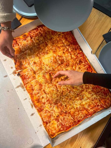Menschen greifen zu Pizza im Quizloft Siegburg