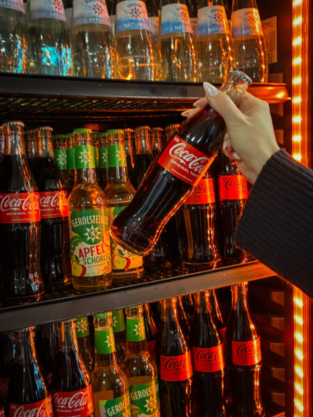 Frau greift nach Getränk aus dem Kühlschrank